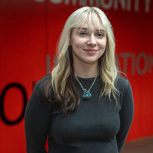 kelly wearing black shirt and red background smiling at camera