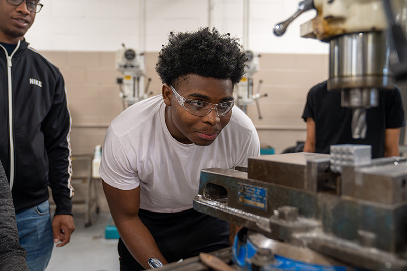 Preston Reasonover watches a machine during a Harbor Pre-Apprenticeship class at the Haas Machining Lab at the Dana Center.