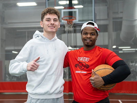 two students on SHAC gym floor with basketball