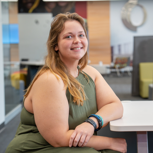 Portrait of kaylee wearing green shirt sitting at table with arms crossed