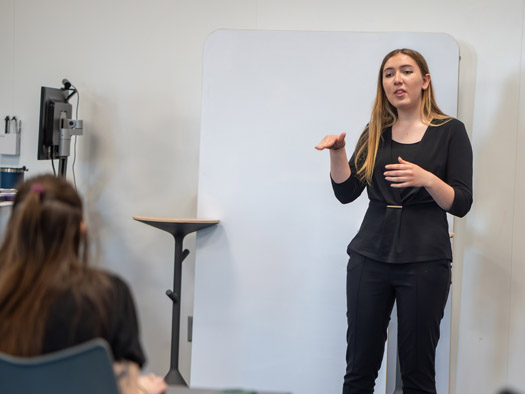 Instructor standing at the front of a class teaching sign language