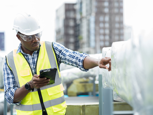 Male construction worker in safety equipment looking at a tablet working