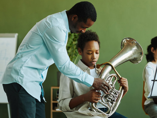student receiving instructions playing a trombone