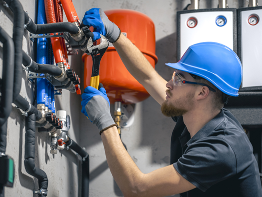 a man wearing a hardhat working on some plumbing