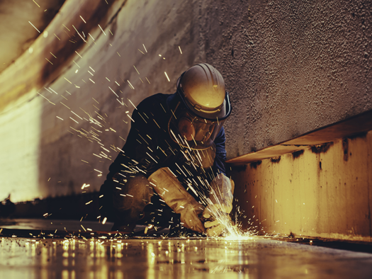 red toned image of somebody welding a plate