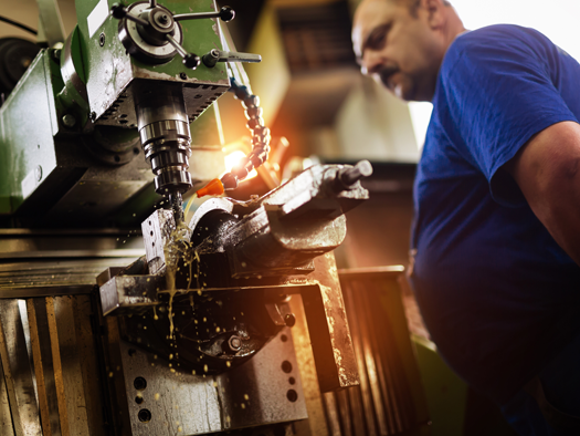 man watching a machine work on metal