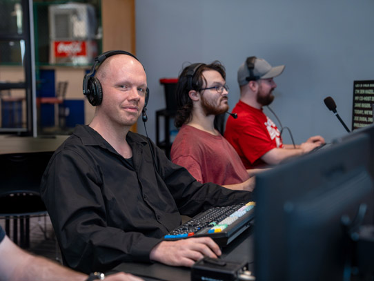 People sitting behind computers directing/producing a broadcast