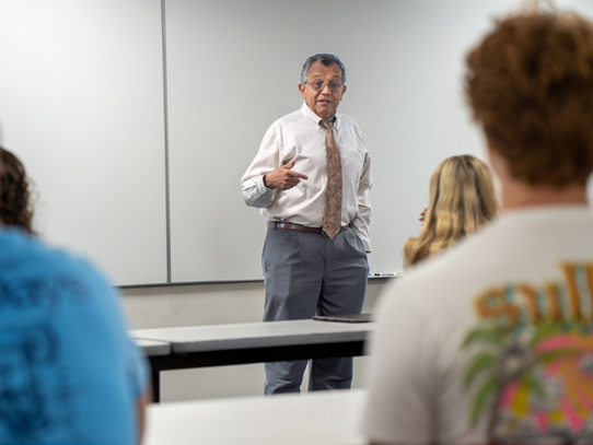 Male instructor standing in front of a classroom giving a lecture
