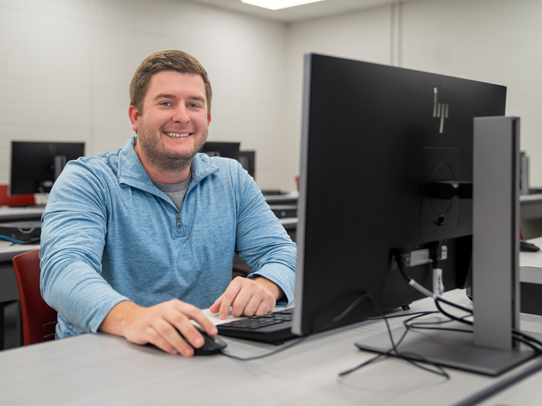 Male student sitting at a desk working on a computer