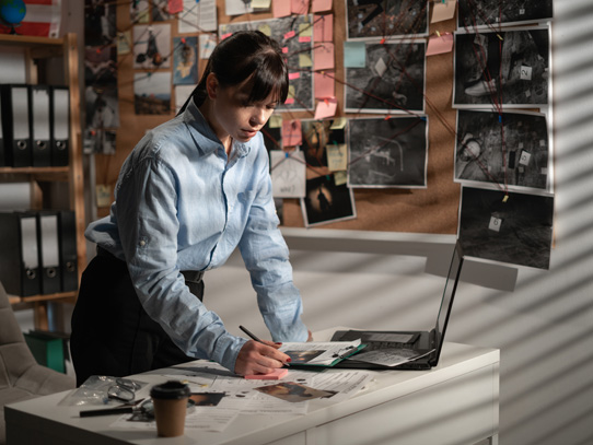Woman sitting in an investigators office working on a computer