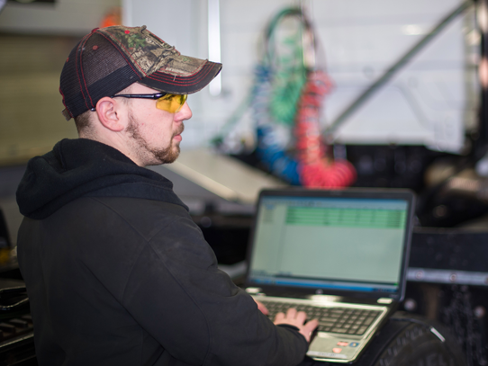 Student sitting in auto shop on a computer