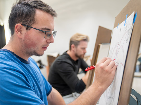 Man standing in front of an easel drawing something