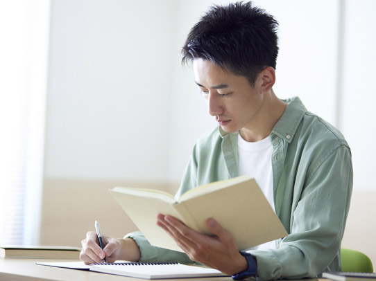 student holding book and writing at the same time