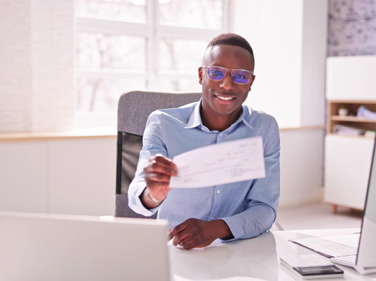 Young student sitting at desk presenting a check or document