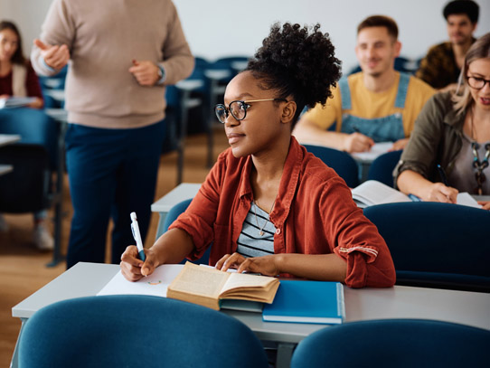 Student sitting at desk paying attention while ready to write something