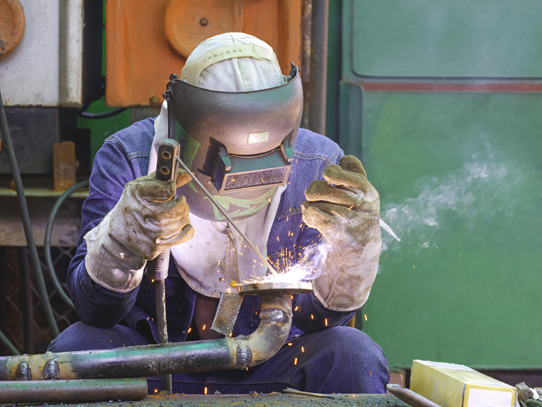 Person welding a pipe in a well lit environment