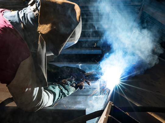 sideview of a person welding with bright blue light