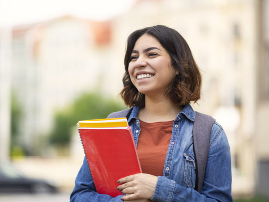 young student smiling looking away from camera holding a red folder