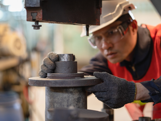 student working on a machine with a piece of metal